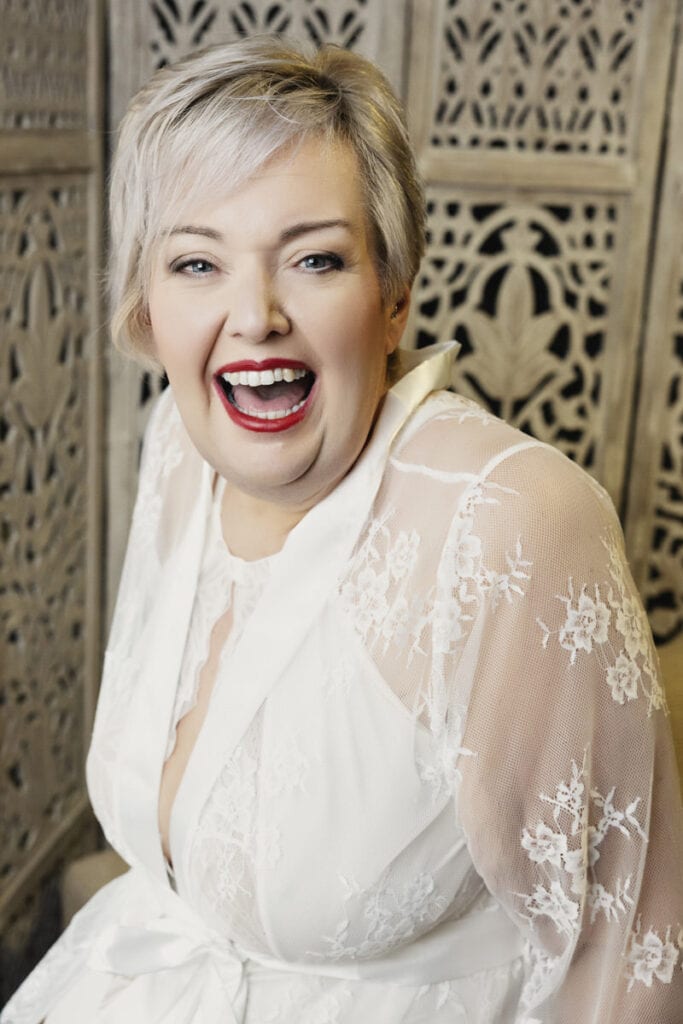 a woman with short hair wearing a white shirt and red lipstick